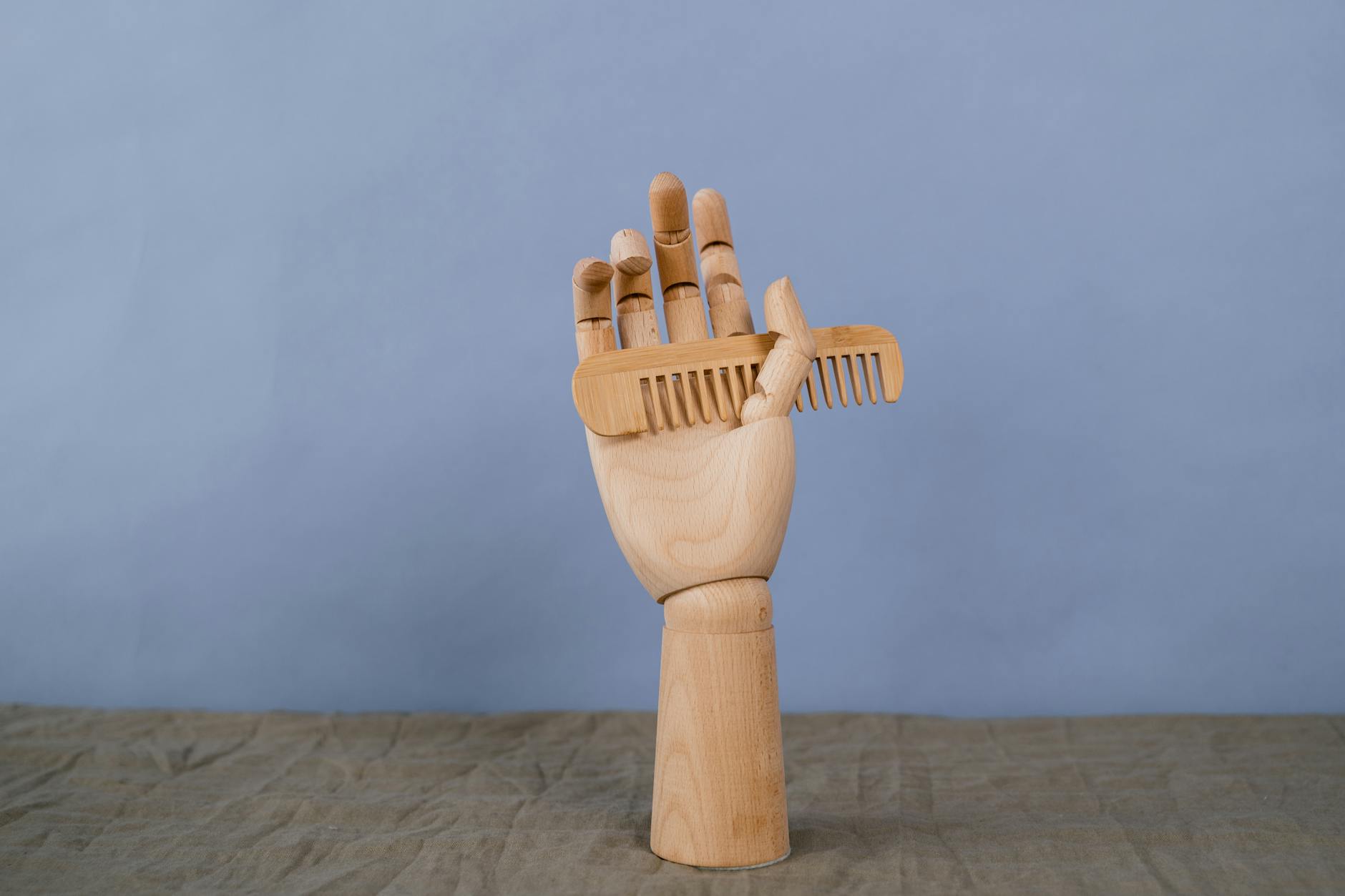 a wooden comb on a wooden hand sculpture